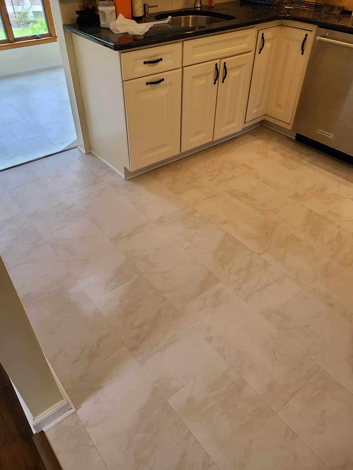 Cream marble-look porcelain tile flooring in a kitchen, installed by Threshing Floors